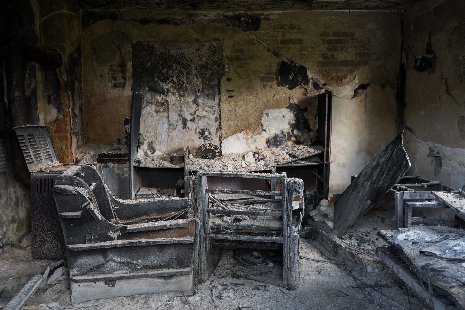 Fire-damaged room with charred furniture and soot-covered walls
